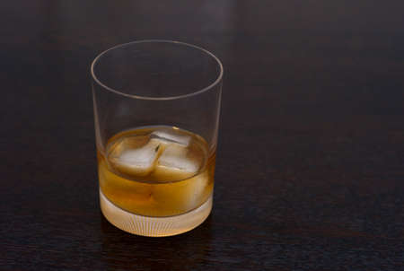 Whiskey, Bourbon, Scotch or Rum on the Rocks in an Elegant Tumbler on a Dark Wooden Table