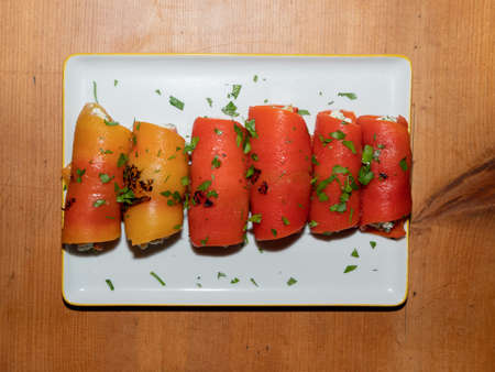 Turkish Appetizer - Red Pepper Rolls Filled With Feta and Nuts on a White Rectangular Plate on a Wood Table - Kirmizi Koz Biber Sarmasiの写真素材