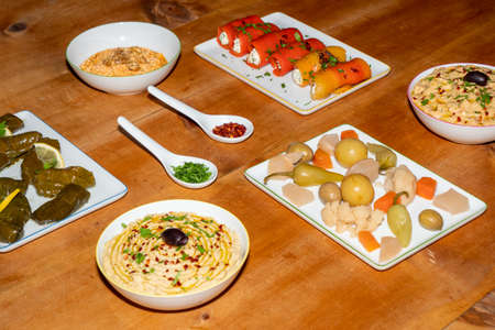Meze Assorted Turkish Starters on a Wooden Table - Stuffed Vine Leaves, Pepper Rolls, Pickles,...