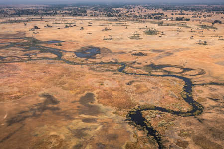 Okavango Delta Aerial, Stunning, Colorful Dry Landscape With Dark Blue River and Orange Arid Savannaの写真素材