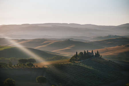 San Quirico d'Orcia - August 20 2020: Podere Belvedere Villa in Val d'Orcia Region in Tuscany, Italy at Sunrise or Dawn, with a Light Ray in the Romantic Early Morning Lightのeditorial素材