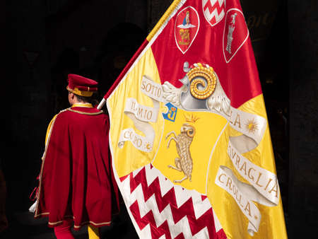 Siena, Italy - August 15 2021: Standard Bearer or Flag Bearer of the Shell or Seashell Contrade, a Page bearing the Banner of the Nobile Contrada del Nicchio and wearing 15th-century costumes..のeditorial素材