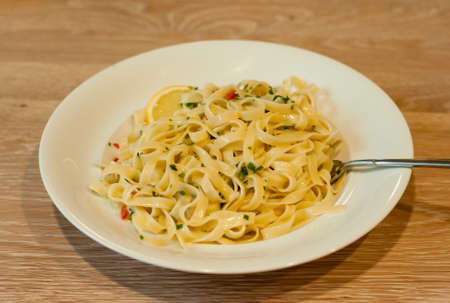 Italian Lemon Pasta or Tagliatelle al Limone on a White Plate with Parsleyの写真素材