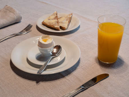 Boiled Egg Breakfast Table with a Glass of Orange Juice and Buttered Toastの写真素材