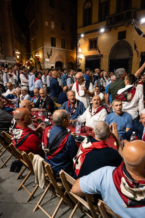 Siena, Italy - August 15 2022: The Grand Contrada Dinner of the Civetta or Little Owl Contrada on the Night before the Palio dell Assunta on Piazza Tolomeiのeditorial素材