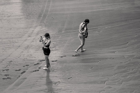 Siena, Italy - August 16 2022:Tourist Taking Mobile Phone Picture on the Rainy Wet Race Trock of the Palio di Siena on the Piazza del Campoのeditorial素材