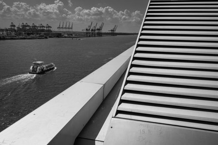 Hamburg, Germany - June 17 2023: River Elbe Landscape with Harbour Cranes, Dockland Building and Ferry Boat in Monochrome Black and Whiteのeditorial素材