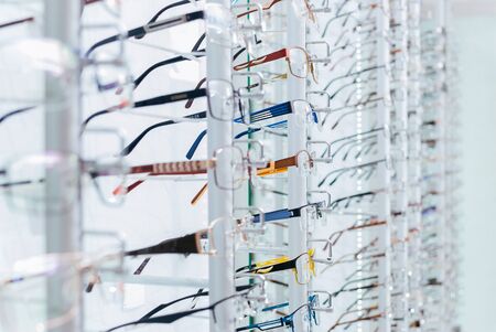 Set of eyeglass frames in the optics store. Close-up showing many eyeglasses in background.の写真素材