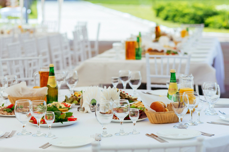 Served for outdoor holiday banquet table with dishes, snack, cutlery, and water glasses.の写真素材