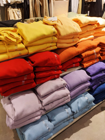 Neatly folded stacks of colorful sweaters on shelves in retail store. Vertical photoの写真素材