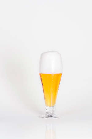 Glass of cold lager beer with foam on a white background isolatedの写真素材