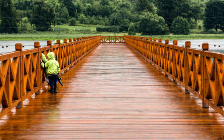 Children playing with toygun on jetty during rainy weather.の写真素材