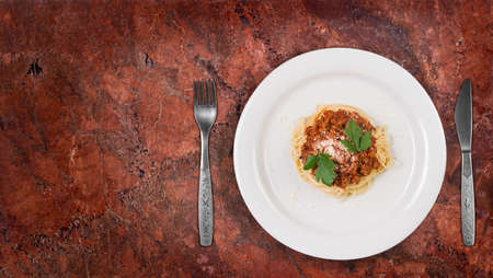 Italian spaghetti pasta with beef and tomato sauce bolognese on white plate on granite kitchen counter topの写真素材
