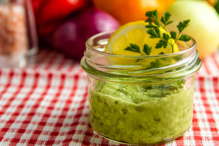 Mexican sauce guacamole in a jar with lemon slice and parsleyの写真素材