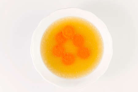 Clear beef broth with carrot slices. bone broth. Bouillon in white bowl.Isolated on white.の写真素材