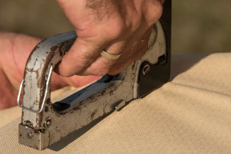 Roof construction building. Man using stapler to attach cover material.の写真素材