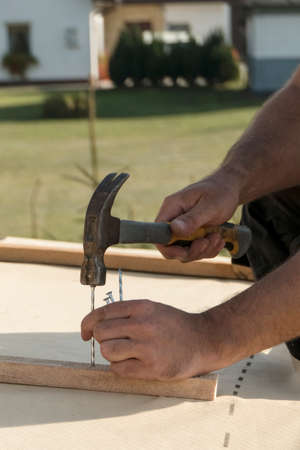 Roof construction building. Man hammering nails in to construction elements.の写真素材