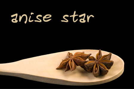 anise star on wooden spoon isolated on black background. Latin name Illicium verum.の写真素材