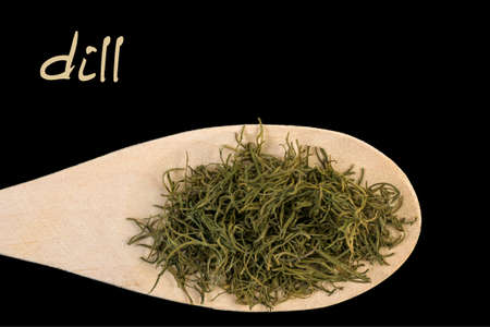 dill on wooden spoon isolated on black background. Latin name Anethum graveolensの写真素材