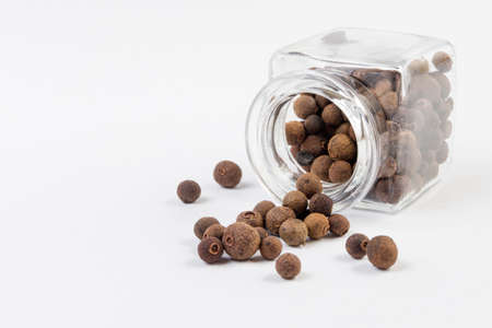 Allspices or Jamaica pepper in jar on white background. Closeup.