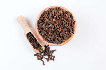 Cloves in wooden bowl and scoop isolated on white background. Closeup.
