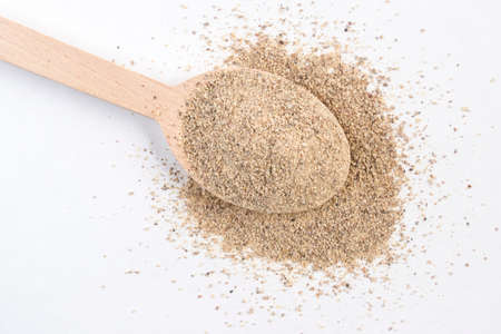 ground white pepper in wooden spoon isolated on white background.top view