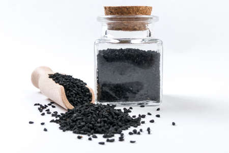 nigella seeds in wooden scoop and jar on isolated on white background