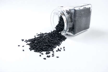 nigella seeds  in a glass jar isolated on white background