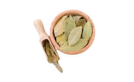 bay leaves in wooden bowl and scoop isolated on white background. top view. Spices and food...