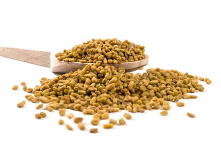 fenugreek seeds on wooden spoon on white backgroundの写真素材
