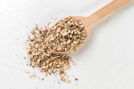 dandelion root or in latin Taraxaci radix in wooden spoon isolated on white background. medicinal...