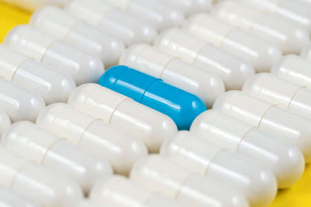 one blue pill among white pillsの写真素材
