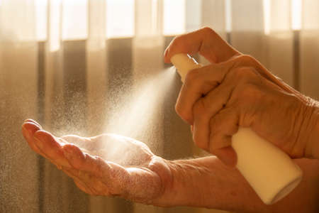 Older caucasian woman applying alcohol spray cleaning hands to helping protect from coronavirus...