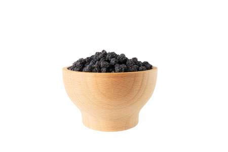 Dried Aronia or black chokeberry - Aronia melanocarpa in latin in wooden bowl isolated on white background.の写真素材