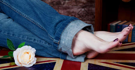 Stretched legs in jeans on a brittish crate and a roseの写真素材