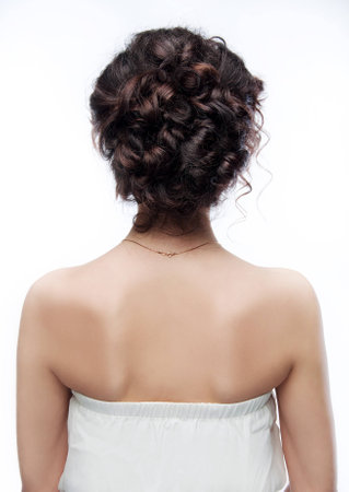 Brunette with an evening hairstyle. View from the back on white background.