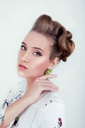 Beautiful sexy woman with natural day makeup wearing green earrings and high hairdo