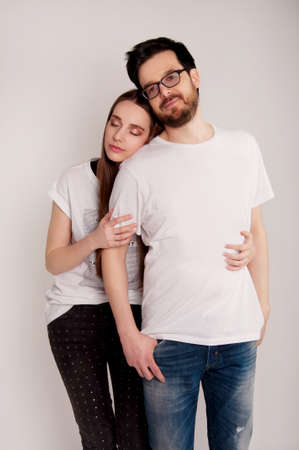 Young couple embracing and looking at the camera, wearing jeans and tee-shirts. Casual style.の写真素材
