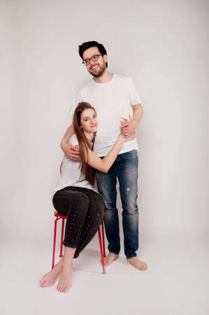 Young couple embracing and looking at the camera, wearing jeans and tee-shirts. Casual style.の写真素材