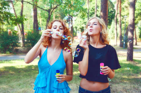 Two friends blowing soap bubbles and playing in the park. Summer activities.の写真素材