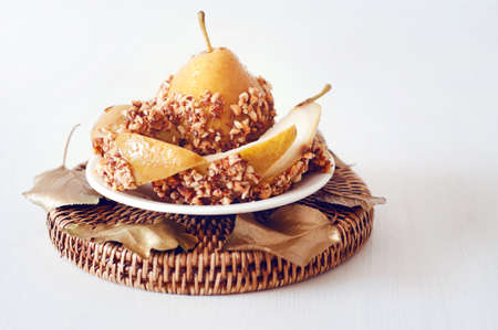Caramelized pear dipped with chopped peanuts decorated with golden leavesの写真素材