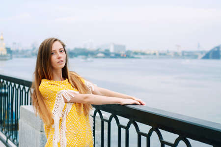 Street city fashion redheaded girl with long hair wearing yellow poncho and boyfriend jeansの写真素材
