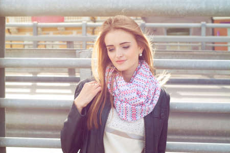 Young fashionable woman in black leather jacket wearing pink scarf and smilingの写真素材