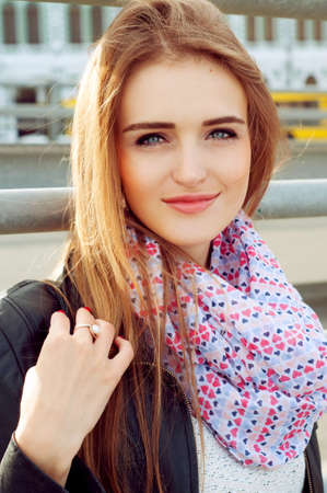 Young fashionable woman in black leather jacket wearing pink scarf and smilingの写真素材