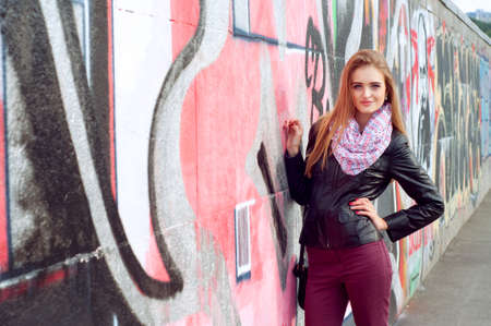 Young fashionable woman in black leather jacket wearing pink scarf and smilingの写真素材