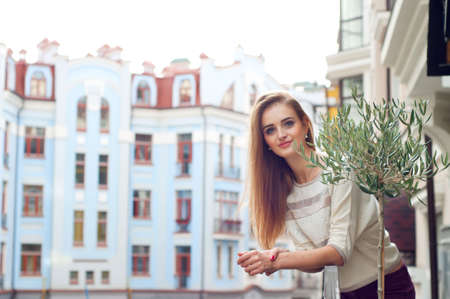 Young blonde woman on her balcony smiling. Urban cityscape and modern buildings.の写真素材