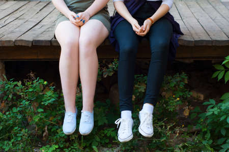 two friends sitting on a wooden bridgeの写真素材