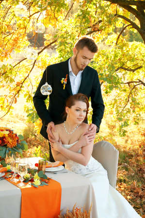 Bride and groom at the wedding table. Autumn outdoor setting. Romantic scenery.の写真素材