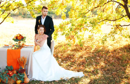 Bride and groom at the wedding table. Autumn outdoor setting. Romantic scenery.の写真素材