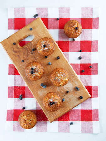 Freshly baked muffins sprinkles with sugar and black currant berries on wooden plateの写真素材